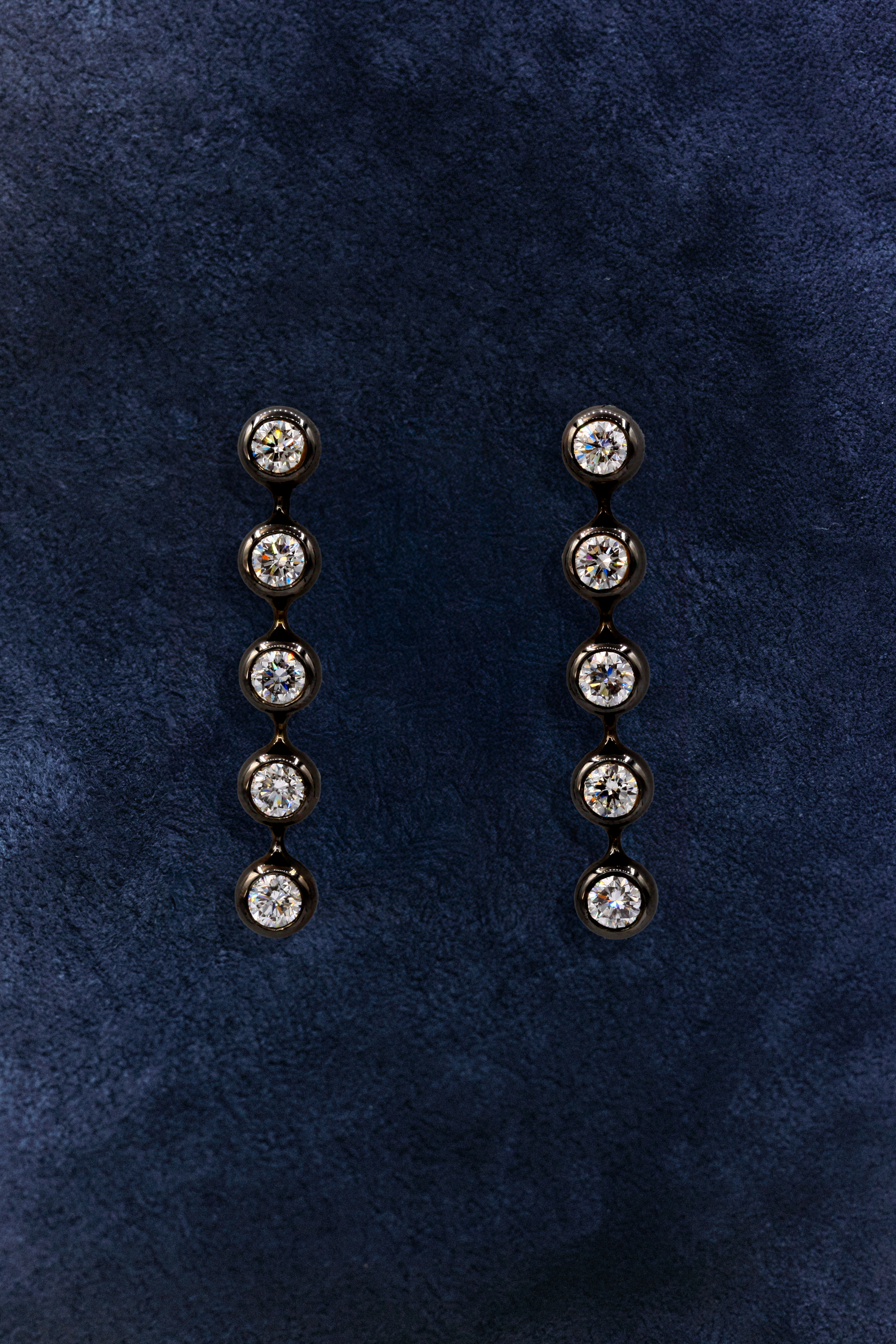 The Anna Cascade Earrings in 18k white gold (palladium alloy) rhodium plated finish (black) set with 10 x laboratory-grown diamonds, E-F vs clarity, 2.5 ctw on a dark background.
