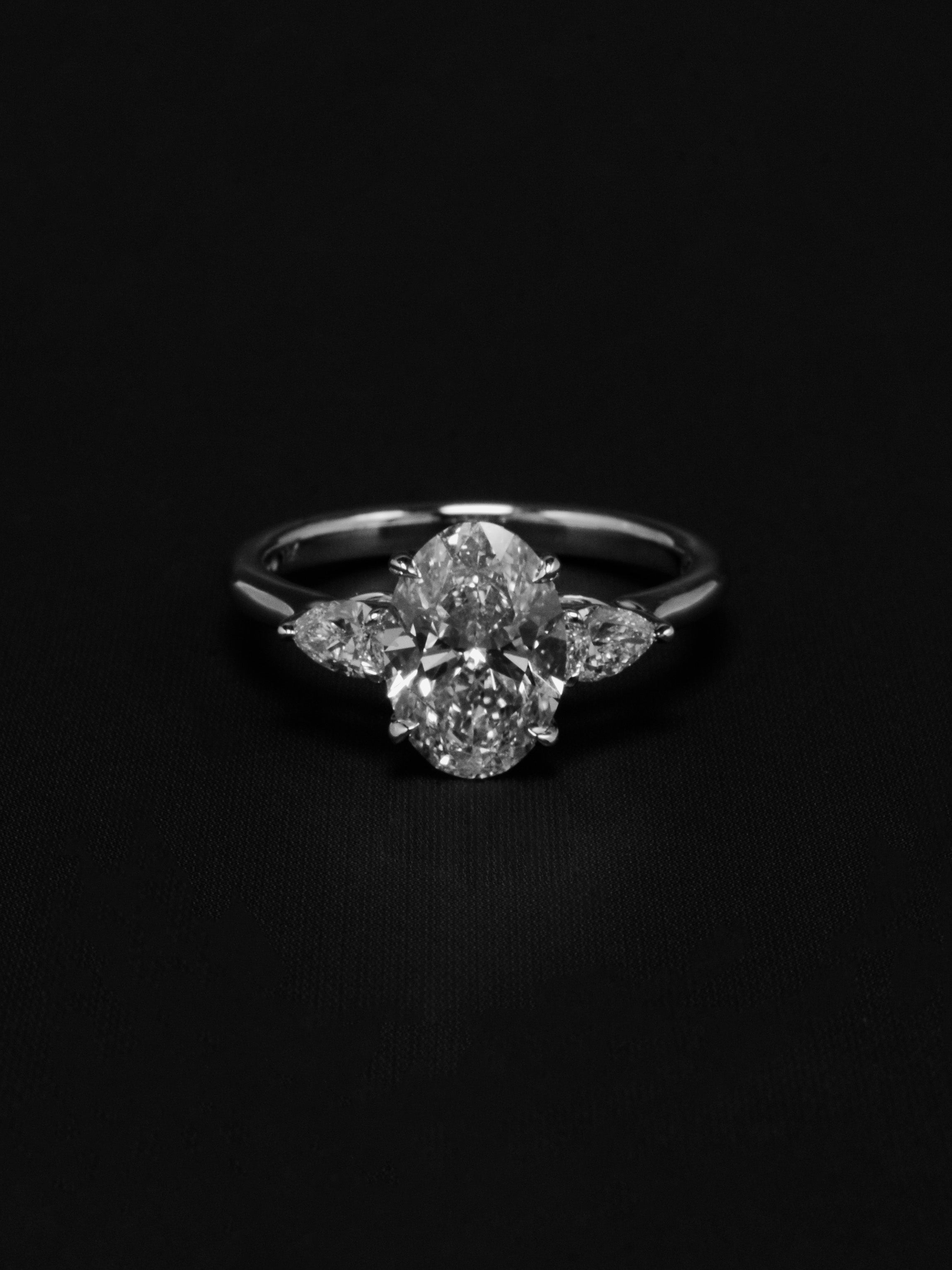3 stone engagement ring on a dark background in a monochromatic style.
