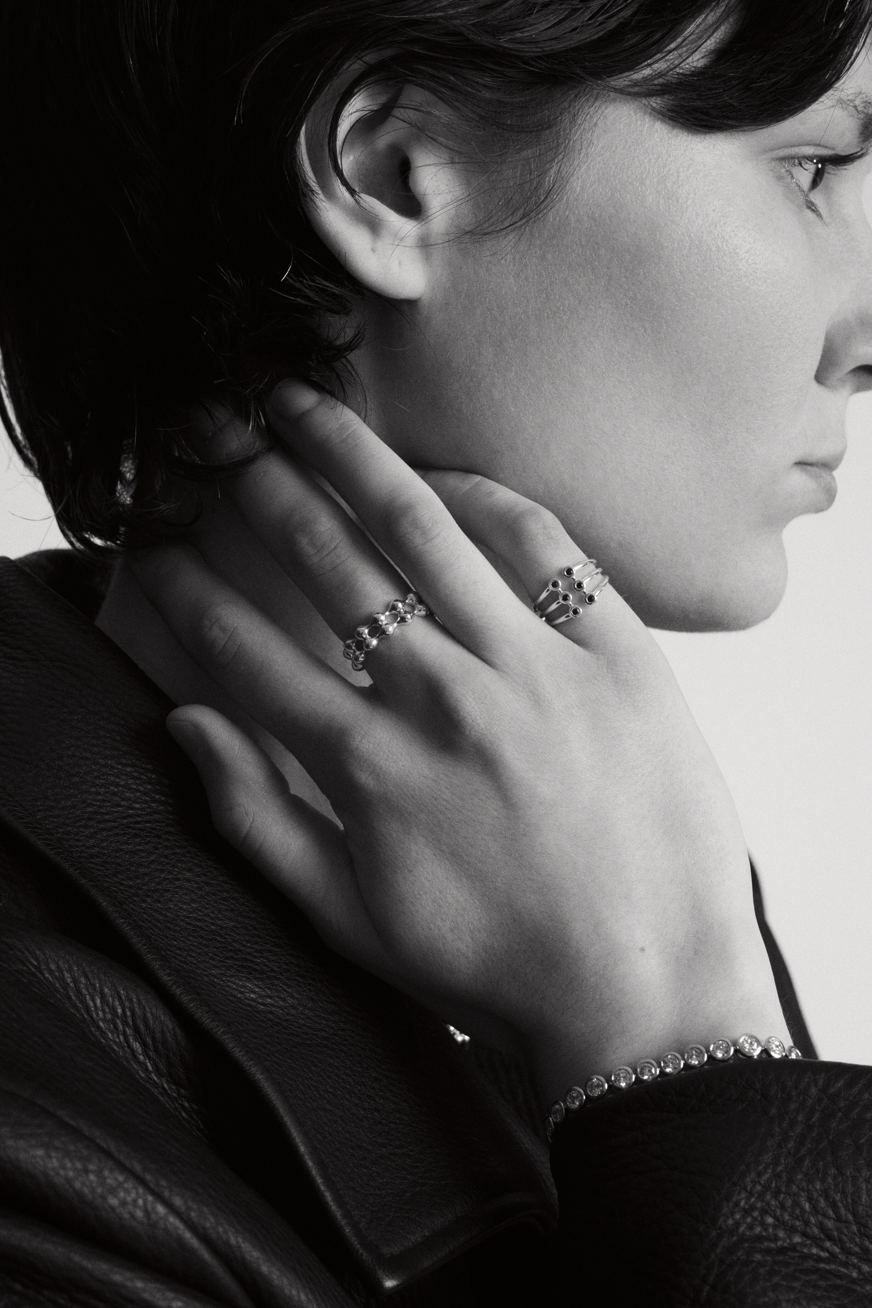 Close-up of a person wearing the Cage ring, Axis Ring and Roller Bracelet in a monochrome style.