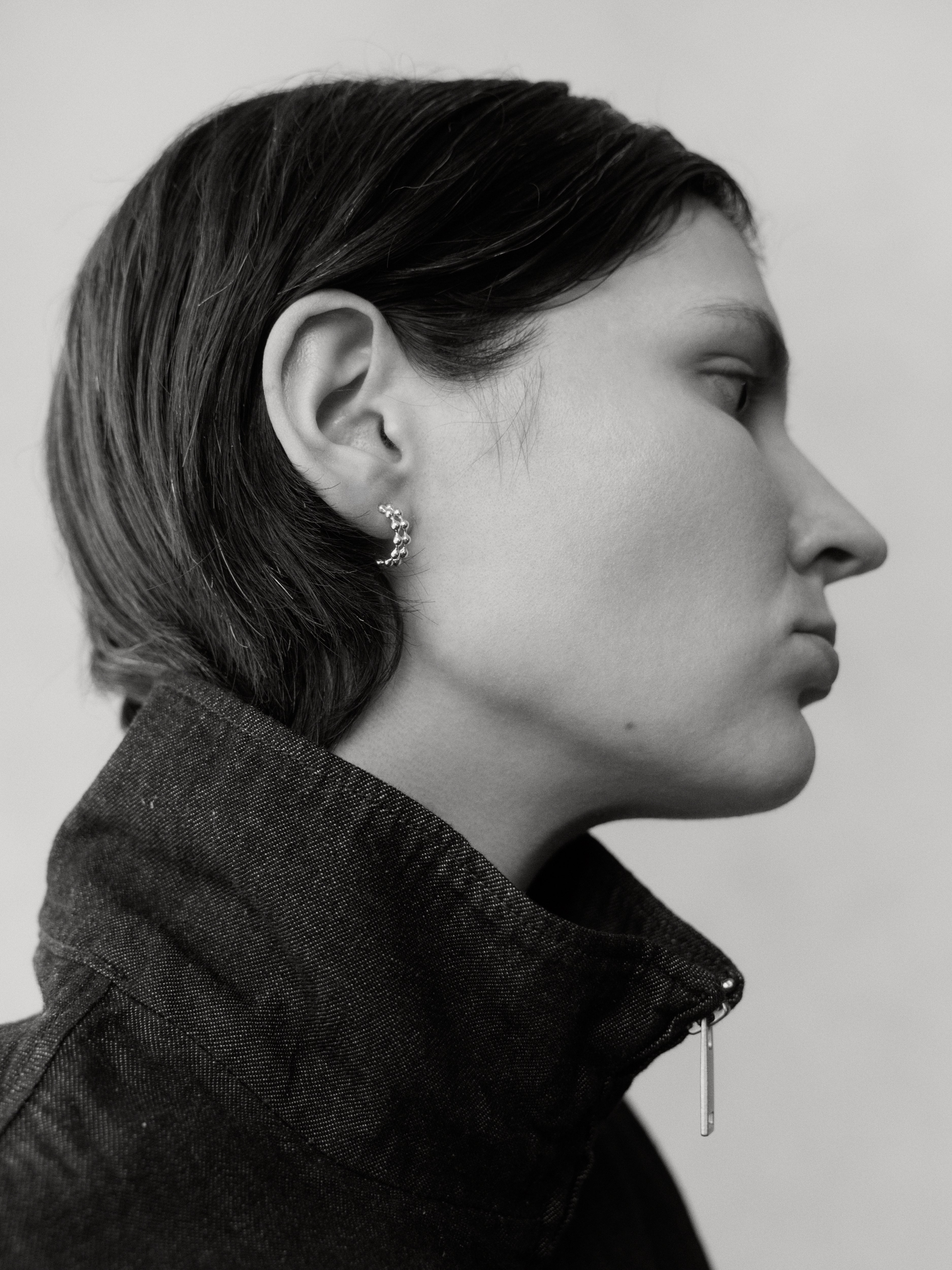 Side profile featuring the Mini Axis Hoops, styled with a structured jacket in a monochromatic style.
